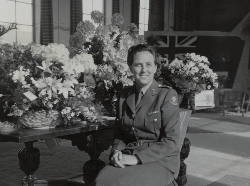 Zwart-witfoto van Dyserinck in uniform zittend voor een tafel vol bloemen.