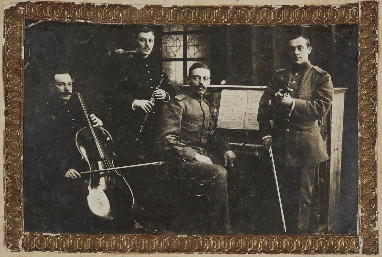 Zwart-wit foto met vier muzikanten die in uniform poseren voor de foto.
