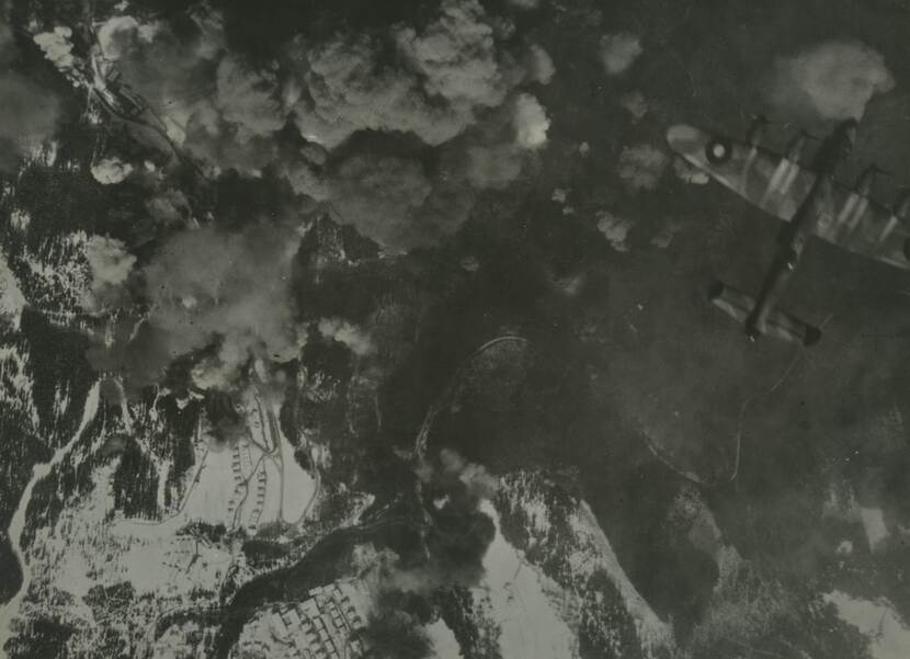 Zwart-witfoto, van boven is een bommenwerper te zien, beneden rookwolken in een besneeuwd landschap.