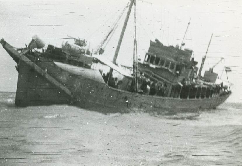 Zwart-witfoto van een varend schip in een onstuimige zee.