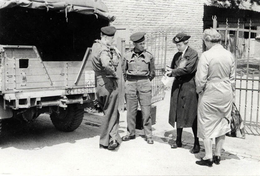 Zwart-witfoto, Van Boetzelaer staat in uniform voor een vrachtwagen met een notitieblok. Naast haar staat een vrouw in burgerkleding en twee mannelijke militairen.