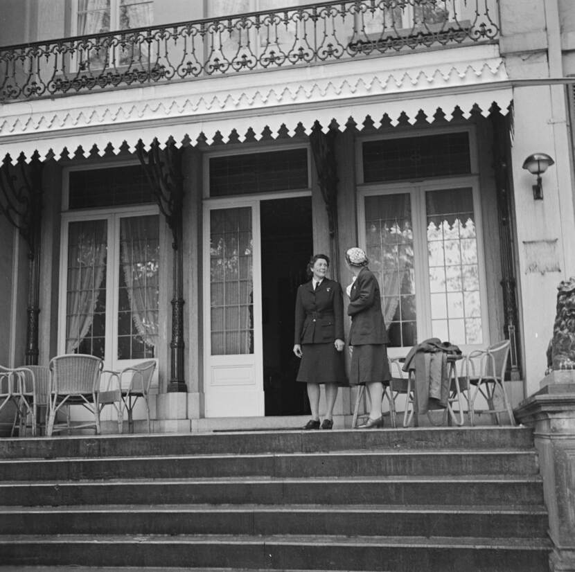 Zwart-witfoto, Knapper en Juliana staan bovenaan de buitentrap met elkaar te praten, Knapper in militair uniform, Juliana in zwart mantelpak.