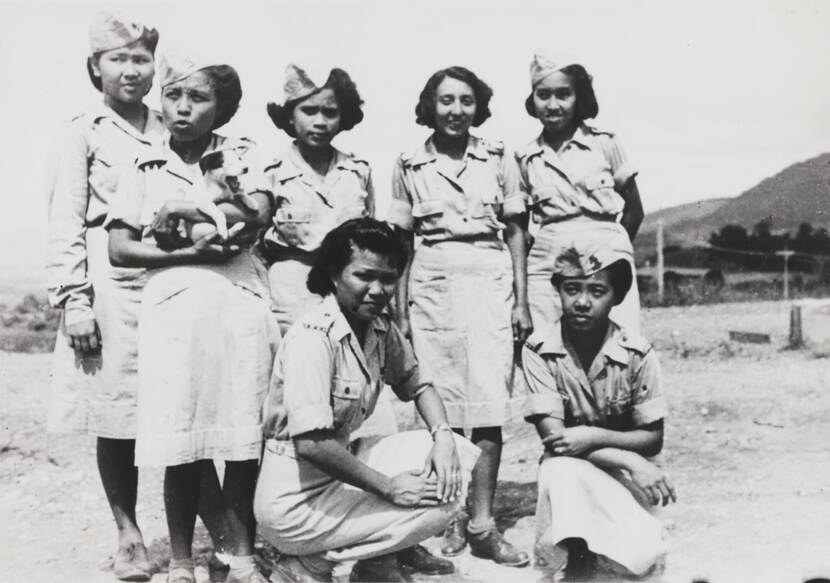 Zwart-witfoto van vrouwen in militair uniform, 1 vrouw heeft een puppy vast.