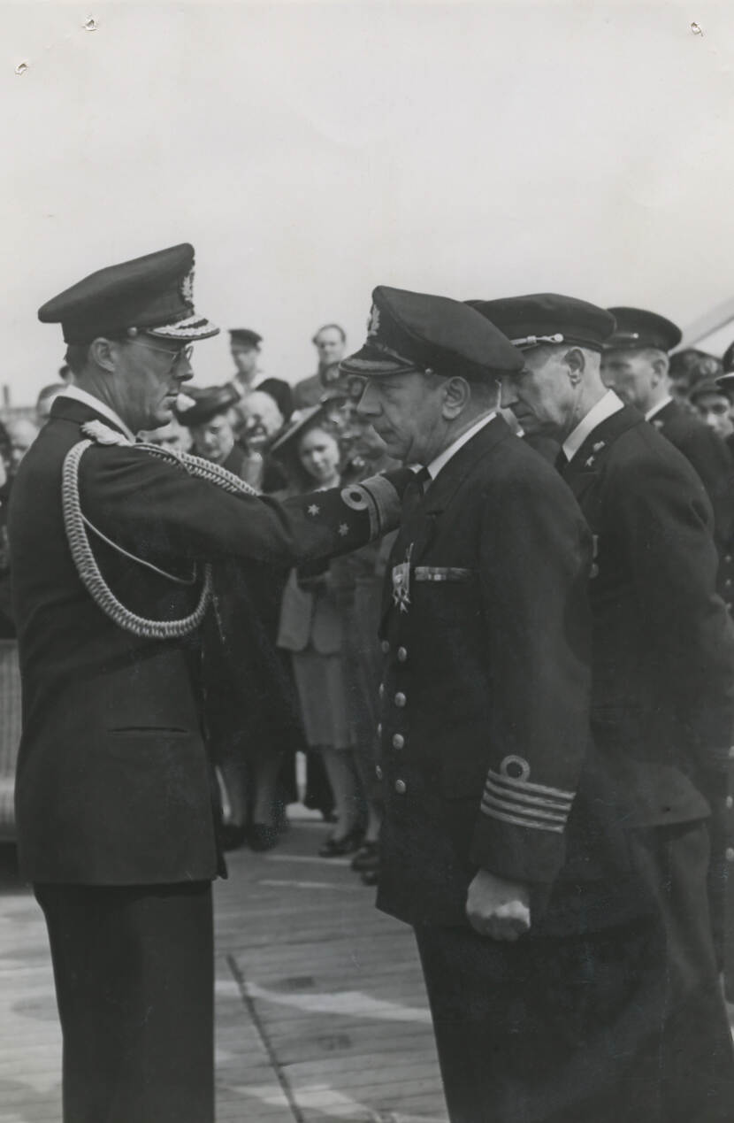 Zwart-witfoto van Romijn en prins Bernhard tijdens de ceremonie. Op de achtergrond staan toeschouwers.